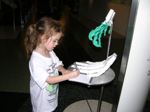 Peo drawing a grasping hand in her evolution journal.
